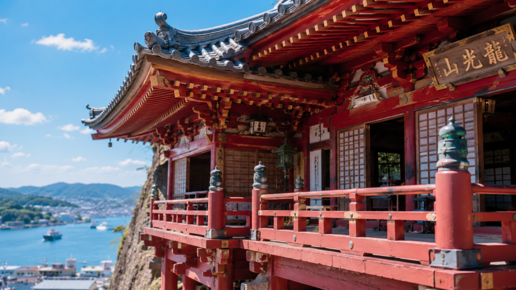 尾道・千光寺の崖に建つ歴史ある朱塗りの本堂と、背景の瀬戸内海のクローズアップ